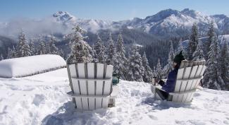 Person sitting in chairs on snowy mountain looking out over tall snowy peaks of Siskiyou Wilderness